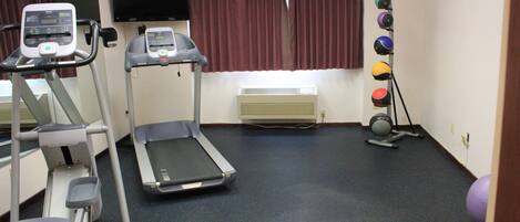 A fitness room with treadmills, an elliptical, a stationary bike, and a set of exercise balls.