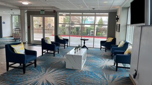 A lobby with blue armchairs, a white coffee table, and large windows offering a view of the outside. - Days Inn by Wyndham Seatac Airport (SeaTac)