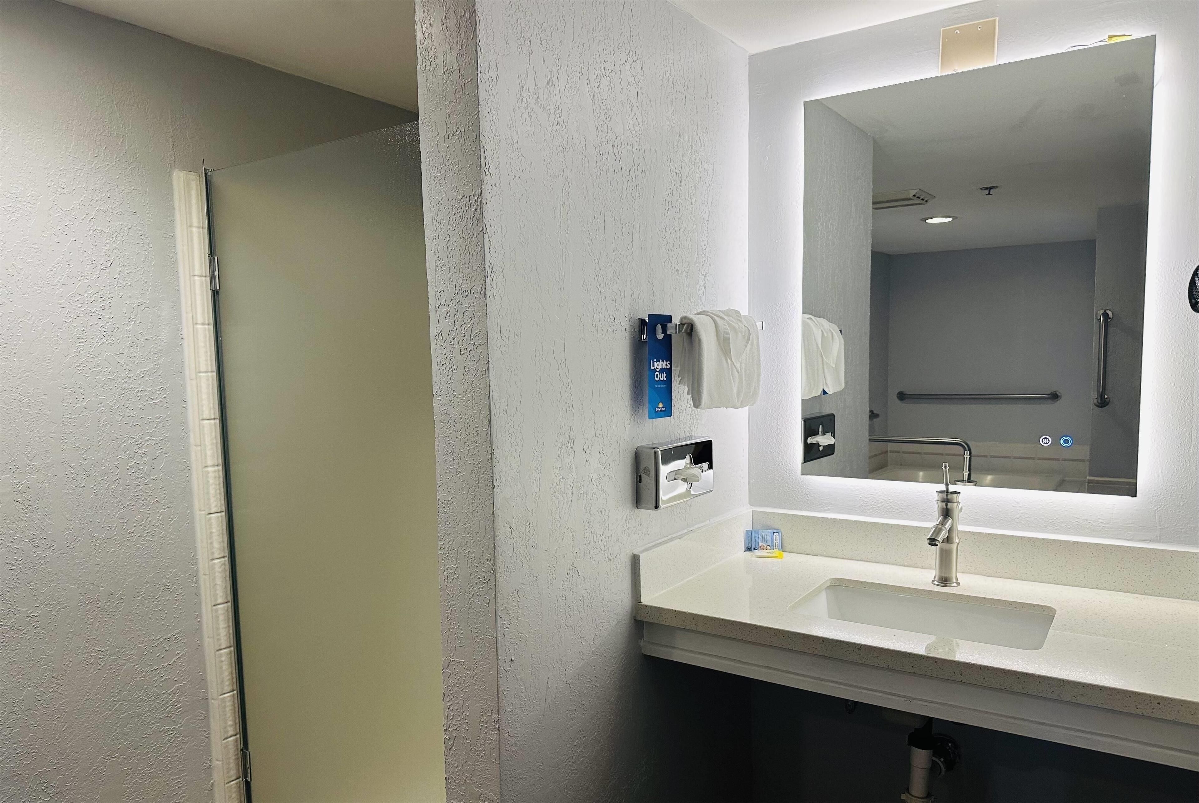 A modern bathroom with a white sink, a mirror, and a towel rack.