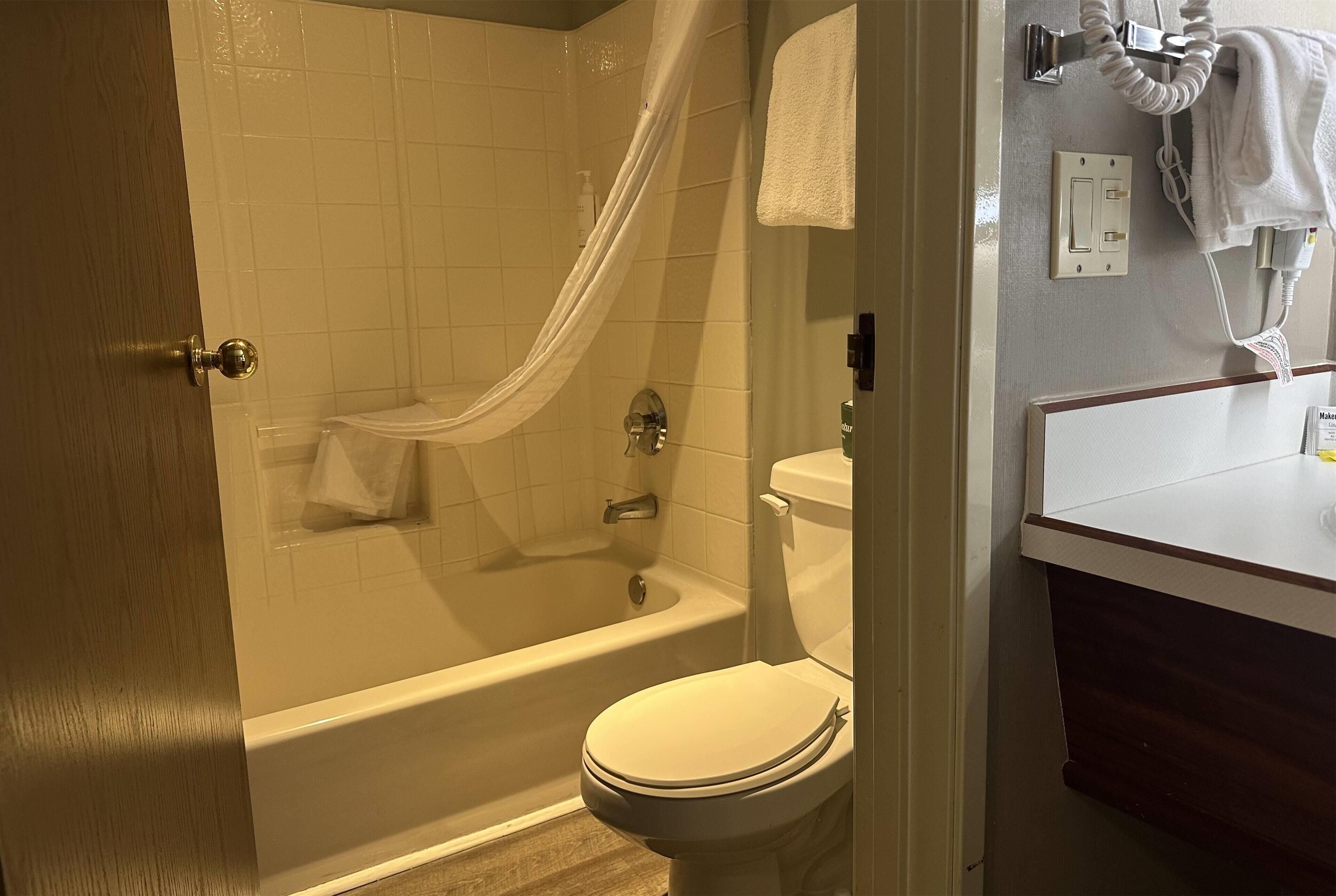 A bathroom with a bathtub, toilet, and a towel rack with a towel.