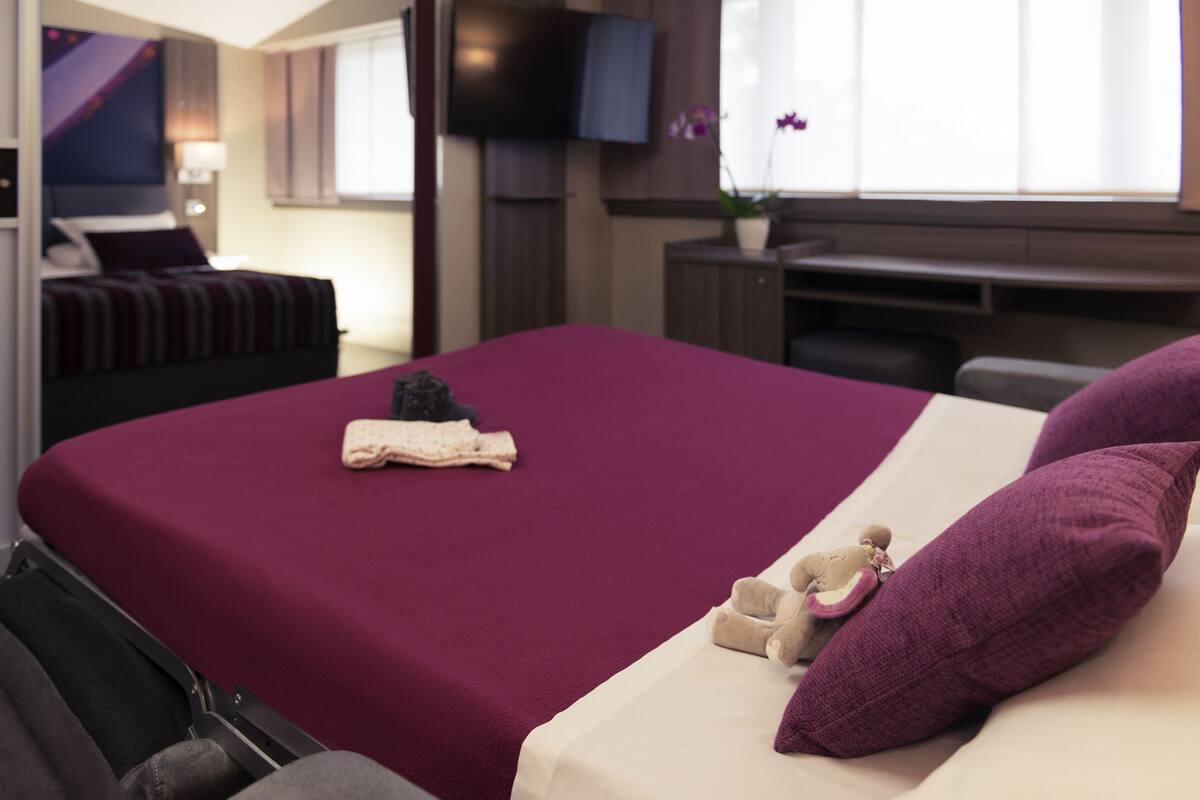 A hotel room with a large bed, a desk, and a television.