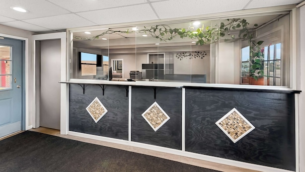 A reception area with a dark marble counter, glass panels, and a hanging plant. - Americas Best Value Inn Marion, OH (Marion)