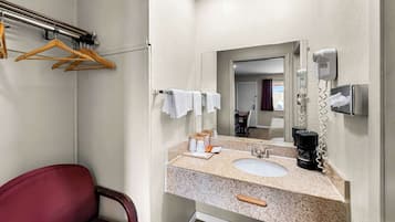 A bathroom with a sink, mirror, towel rack, and a chair.