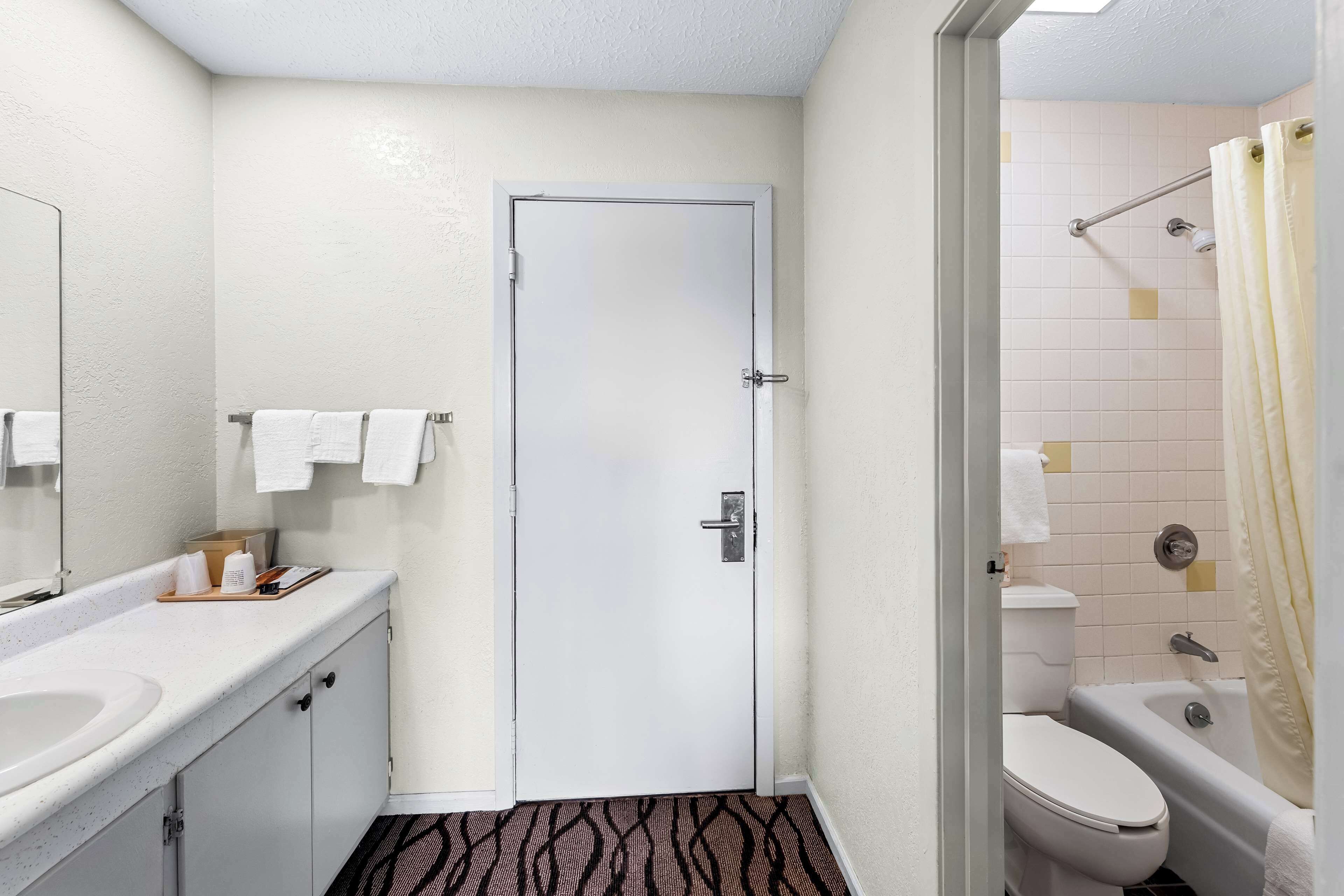 A bathroom with a white sink, toilet, and shower area.