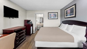 A hotel room with a large bed, a desk with drawers, a television, and a painting on the wall. - Americas Best Value Inn Marion, OH (Marion)
