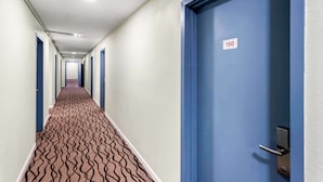 A hotel hallway with blue doors, a patterned carpet, and a number sign on one door. - Americas Best Value Inn Marion, OH (Marion)