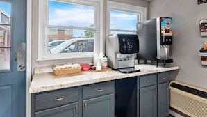A kitchen with a coffee machine, a basket of bread, and a window with a view of a car outside. - Americas Best Value Inn Marion, OH (Marion)