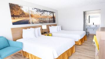 Habitación de hotel con dos camas, un escritorio, una silla, baño y un ventanal grande.