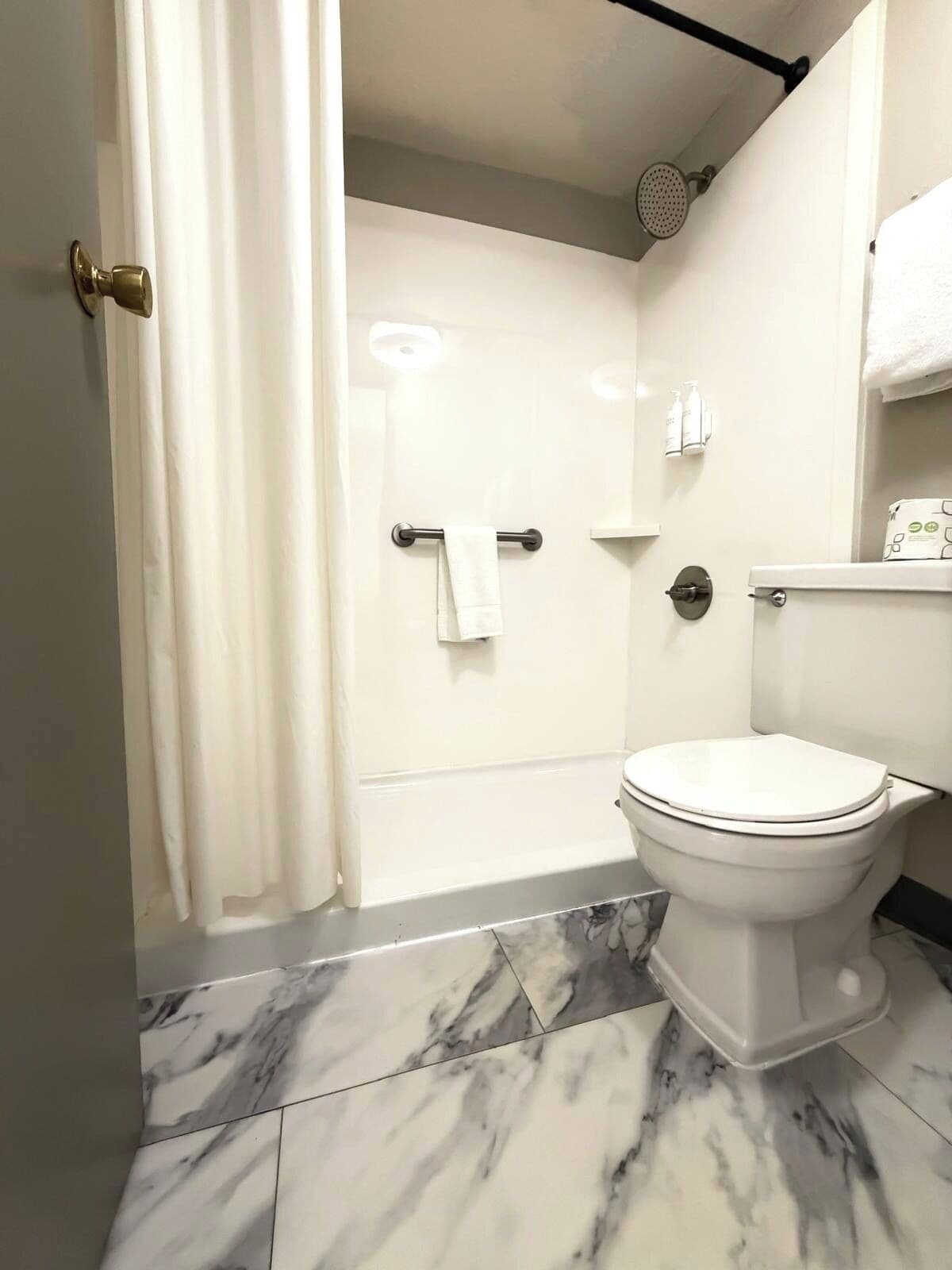 Une salle de bain avec des toilettes, une douche et un sol en marbre.