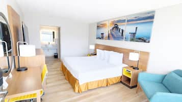 Een hotelkamer met een bed, bureau, stoel en een schilderij van een pier.