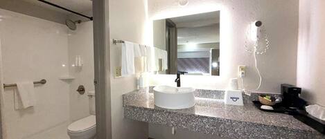 A bathroom with a white sink, a mirror, a towel rack, and a shower area.
