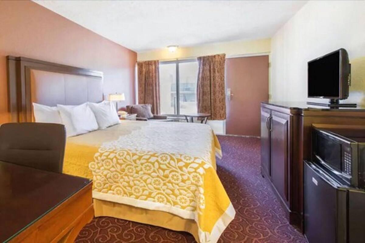 A hotel room with a bed, a desk, a television, and a minibar.