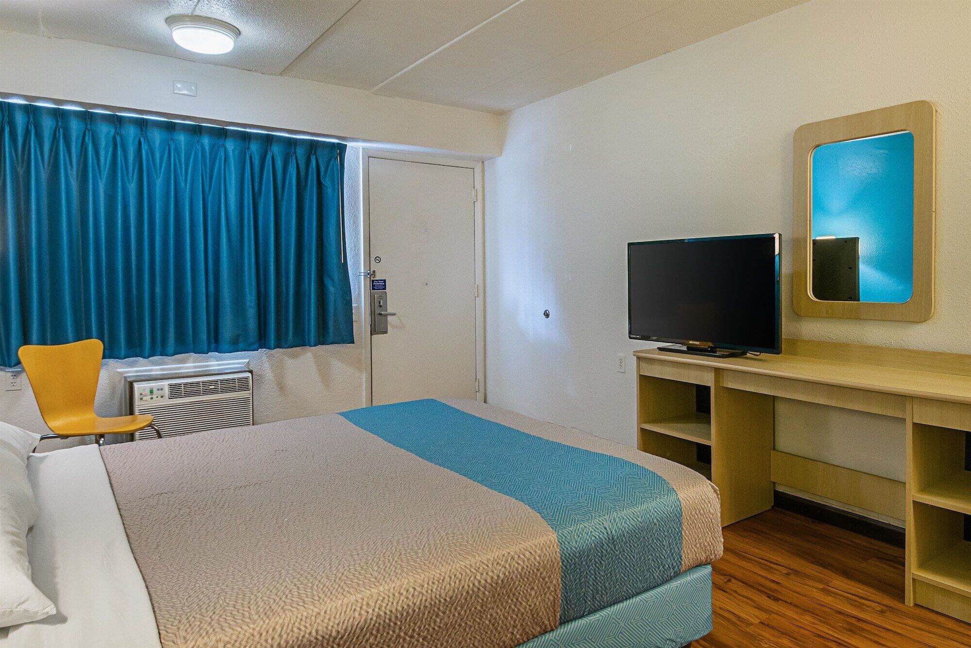 A hotel room with a bed, a television, a desk, and a chair.