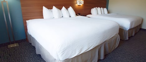 Habitación de hotel con dos camas, una mesita de noche, una lámpara y una lámpara de pared.