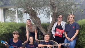 A group of people sitting and standing outdoors with a tree and a building in the background. - Ibis Lorient-Caudan (Caudan)