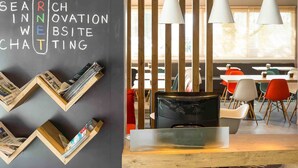 Un espacio de trabajo moderno con una pizarra mostrando varias palabras relacionadas con los negocios, estanterías de madera y un área de descanso con mesas y sillas.