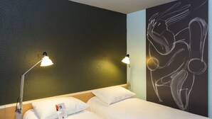 Habitación de hotel con dos camas, cada una con ropa blanca y almohadas, y dos lámparas de noche.