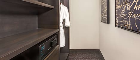 A modern bathroom with dark wood shelving, a white robe hanging, and a wall with golden signatures.