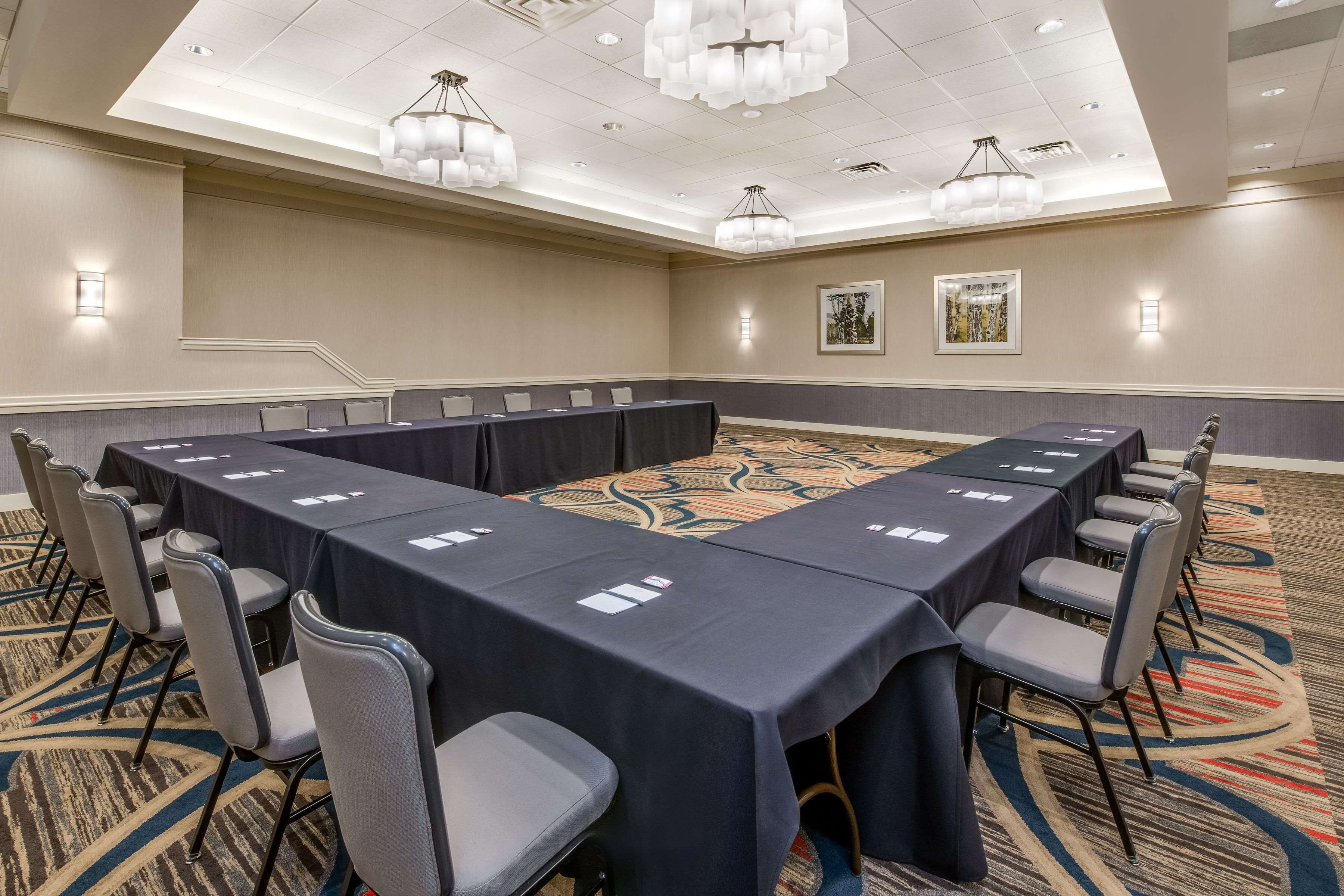 A conference room with a long table, chairs, and a carpeted floor.