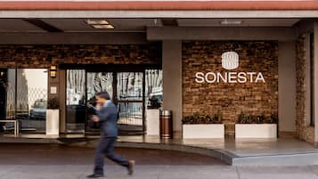 A hotel entrance with a stone facade, a glass door, and a sign reading "SONESTA".