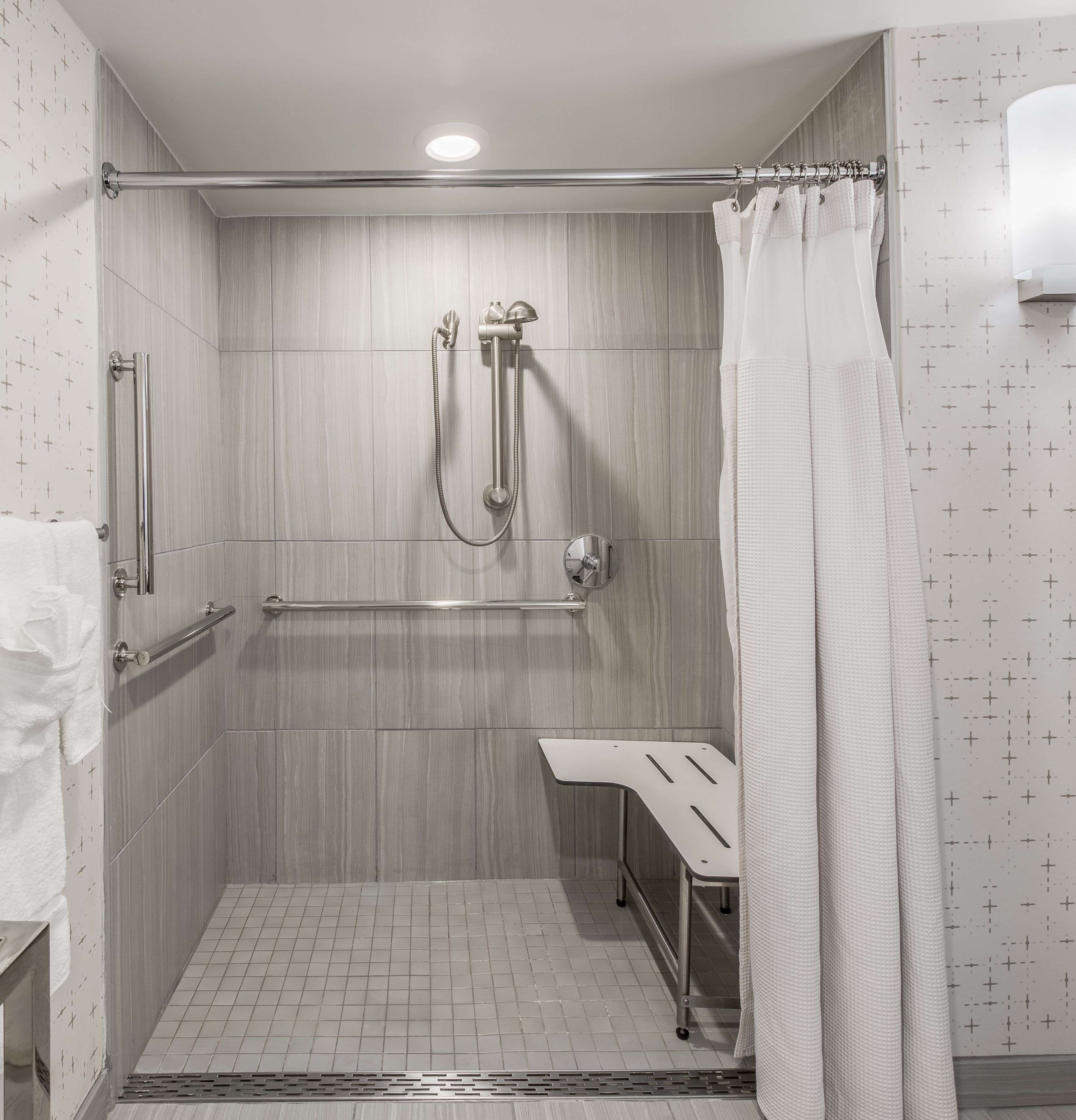 Une douche à l’italienne équipée d’une barre d’appui, d’un pommeau de douche amovible et d’un porte-serviettes.