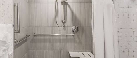 Une douche à l’italienne équipée d’une barre d’appui, d’un pommeau de douche amovible et d’un porte-serviettes.