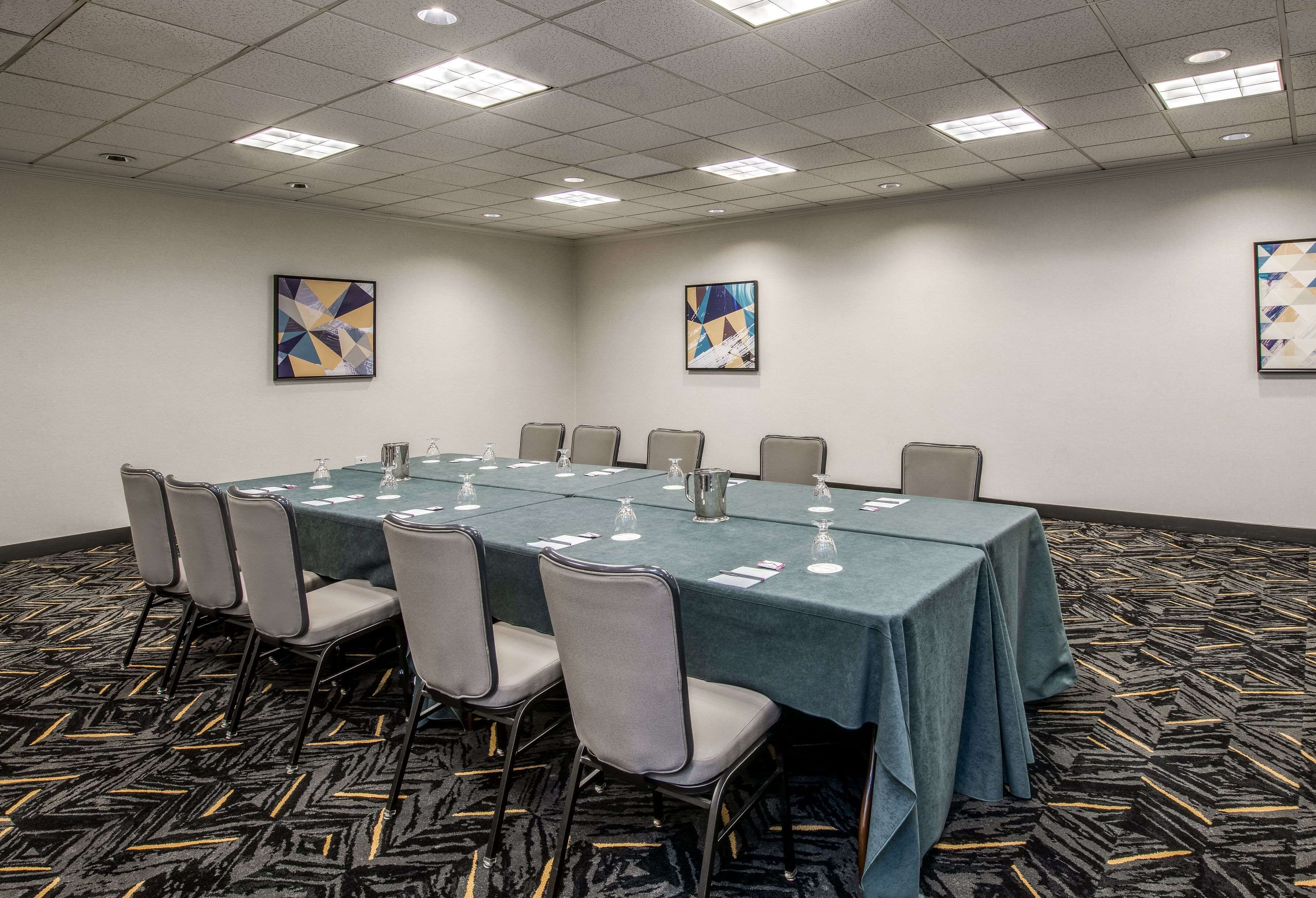 A conference room with a long table, chairs, and artwork on the walls.