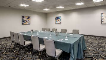 Un salón de conferencias con una larga mesa, sillas y obras de arte en las paredes.