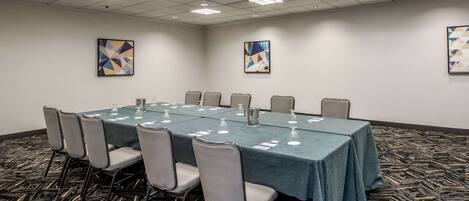 A conference room with a long table, chairs, and artwork on the walls.