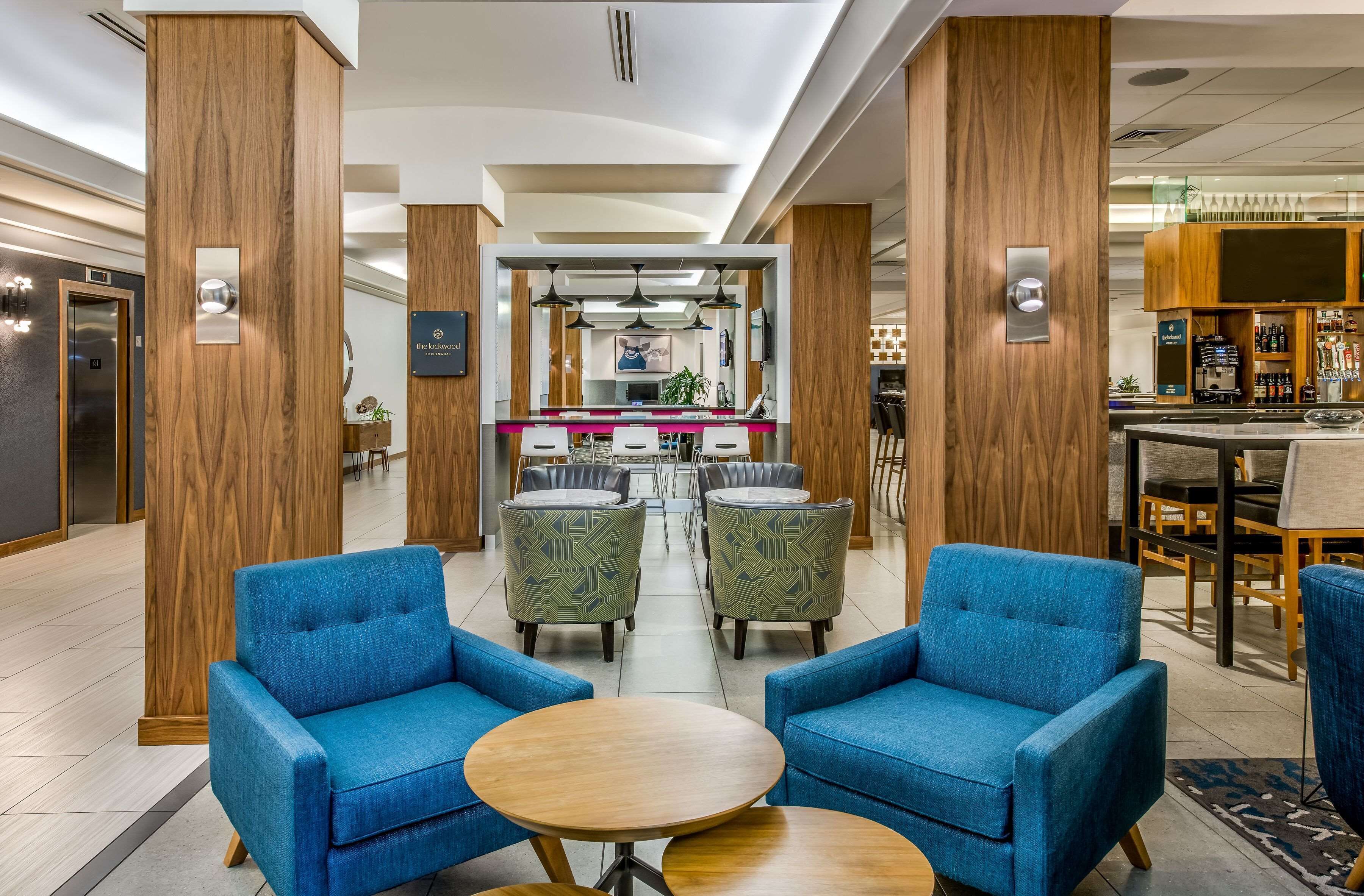 A hotel lobby with wooden pillars, a reception desk, and a bar area.