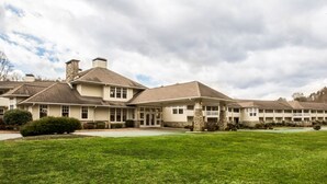 A large, multi-story building with a symmetrical facade, multiple chimneys, and a well-maintained lawn. - SureStay by Best Western Cherokee on the River (Cherokee)