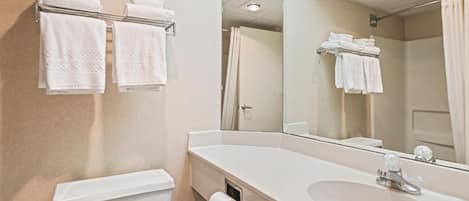A bathroom with a toilet, sink, mirror, and towel rack.
