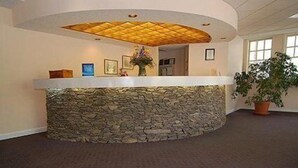 A reception area with a stone counter, framed pictures, and a potted plant. - SureStay by Best Western Cherokee on the River (Cherokee)