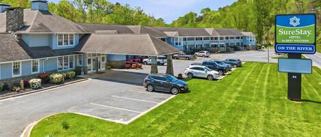 A hotel with a parking lot, a sign for SureStay Hotel by Best Western, and a row of rooms with a view of the river.