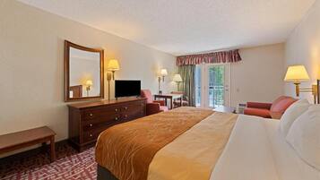 A hotel room with a large bed, a desk, a chair, a television, and a window with curtains.