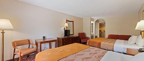 Une chambre d’hôtel avec deux lits, un bureau, une chaise, une télévision et une lampe.