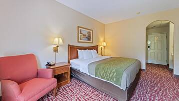 A hotel room with a bed, a desk, a chair, and two wall-mounted lamps.