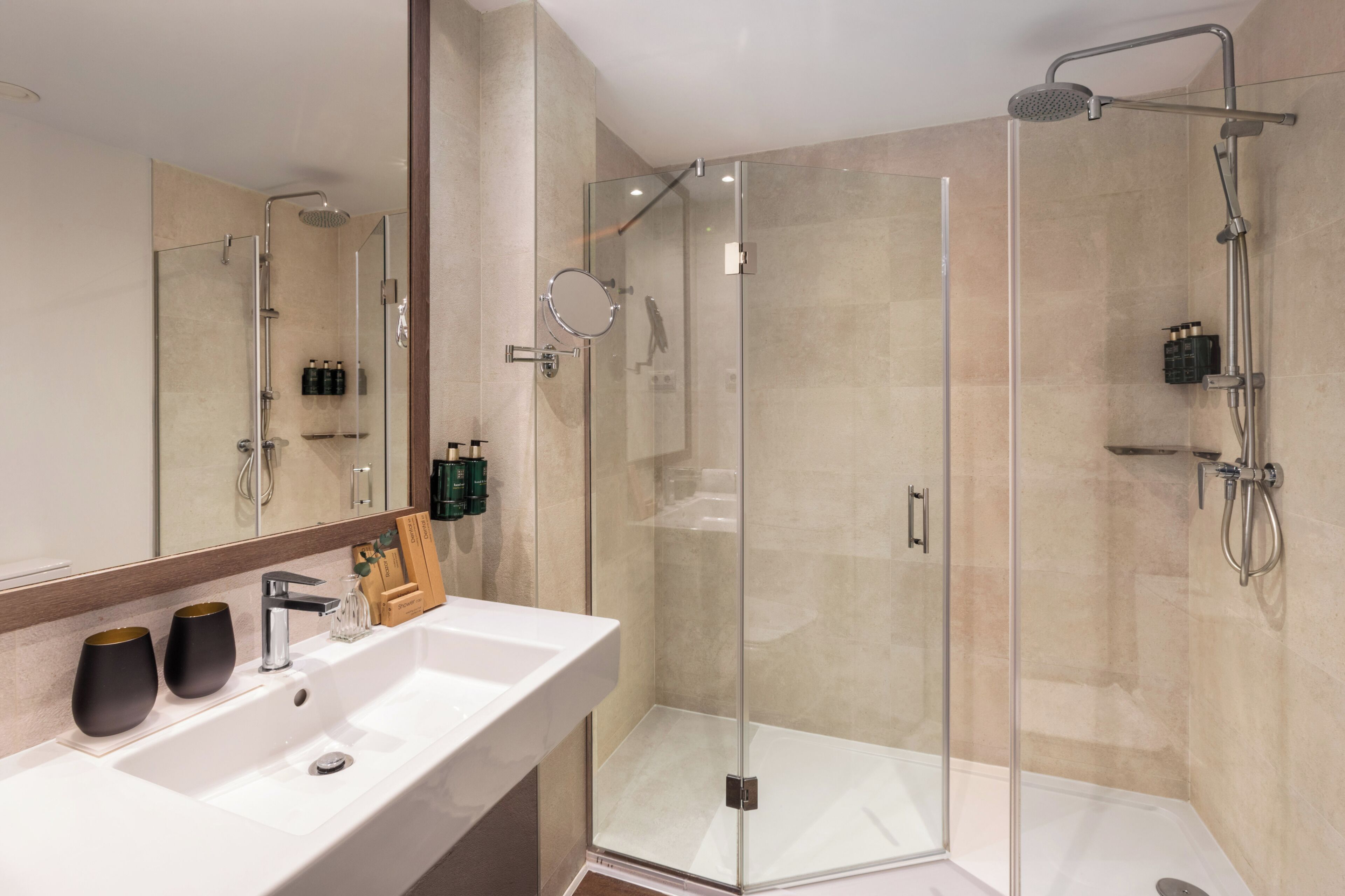 A modern bathroom with a glass-enclosed shower, a large mirror, and a white sink.