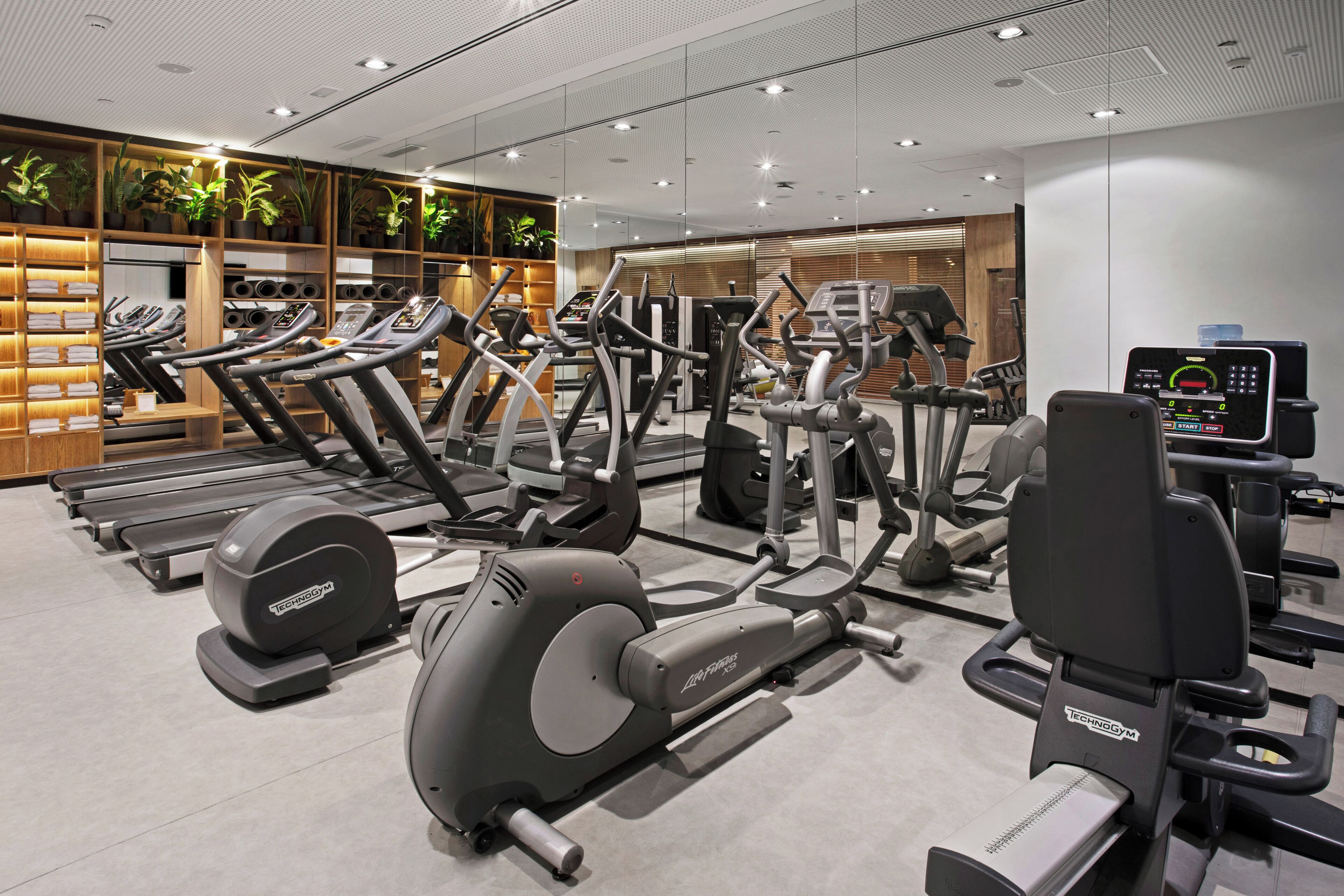 Ein modernes Fitnessstudio mit mehreren Laufbändern, Crosstrainern und Gewichtsgeräten.