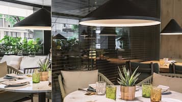 A modern dining area with round tables, green glassware, and woven plant pots.