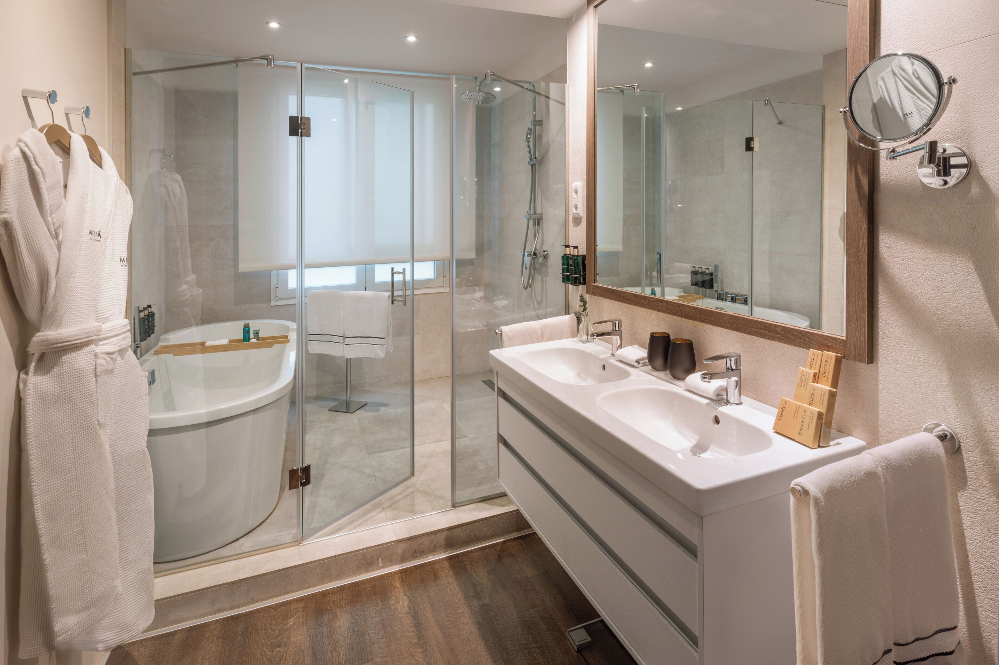 Un baño moderno con ducha de vidrio, tocador doble y un espejo grande.