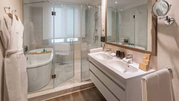 Un baño moderno con ducha de vidrio, tocador doble y un espejo grande.