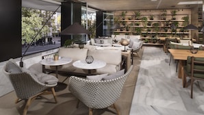 A modern interior with a sofa, chairs, tables, and a plant wall. - Melia Madrid Serrano (Madrid)