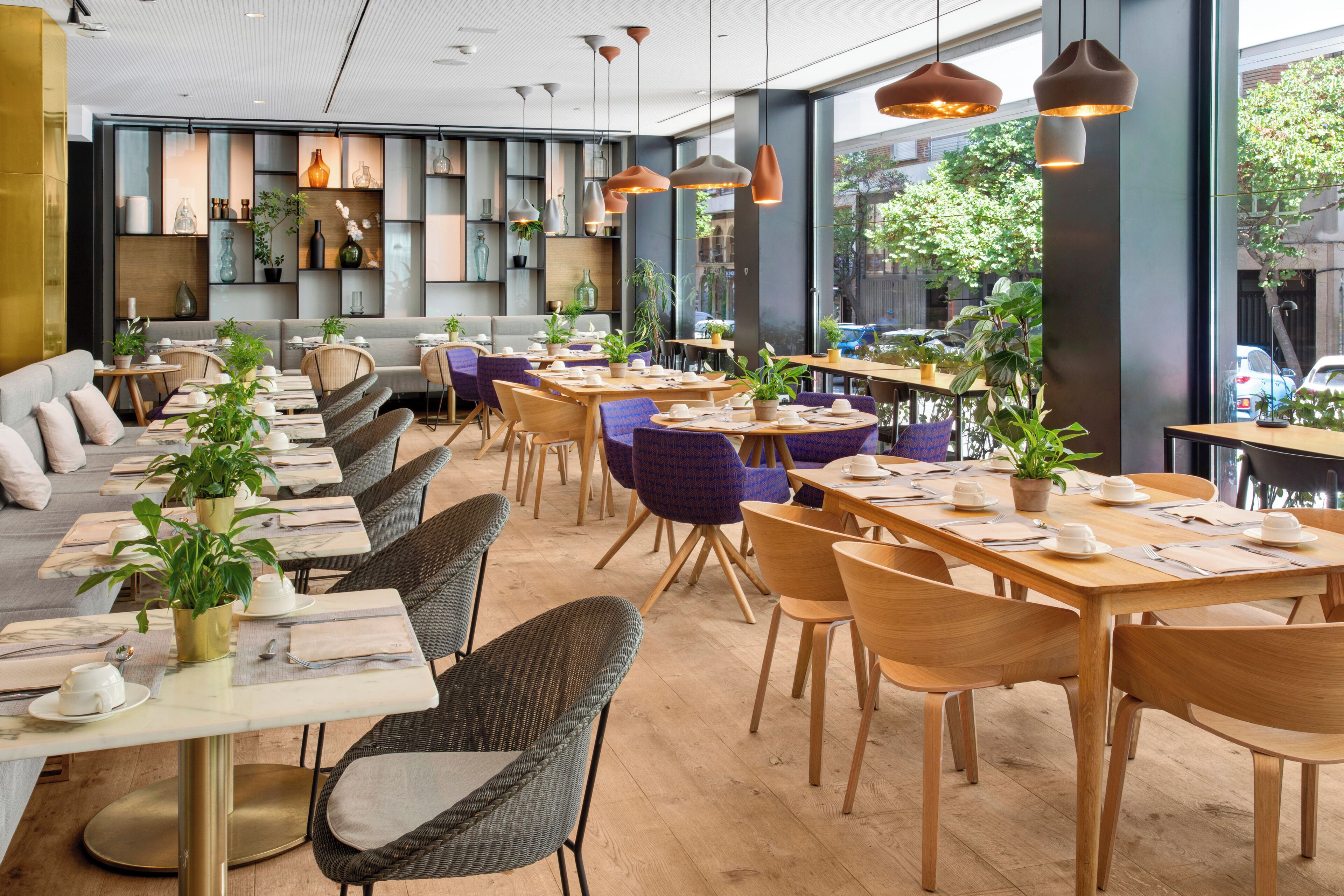 Un restaurante moderno con mesas comunitarias largas, cabinas individuales y diferentes opciones de asientos.