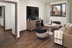 Ein modernes Wohnzimmer mit einer Couch, einem Couchtisch und einem an der Wand befestigten Fernseher.