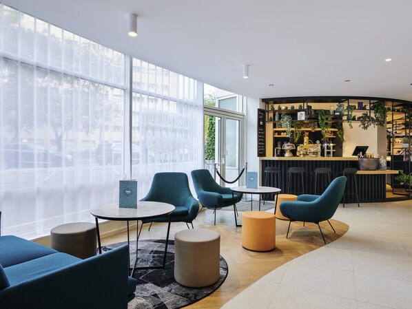 A modern lounge area with seating, a bar, and large windows. - Hotel Mercure Paris La Défense (Courbevoie)