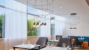 Un'area ristorazione moderna con tavoli, sedie e lampade a sospensione.