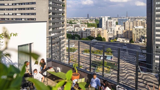 Una terrazza sul tetto con vista sulla città, tra cui grattacieli e una torre in lontananza.
