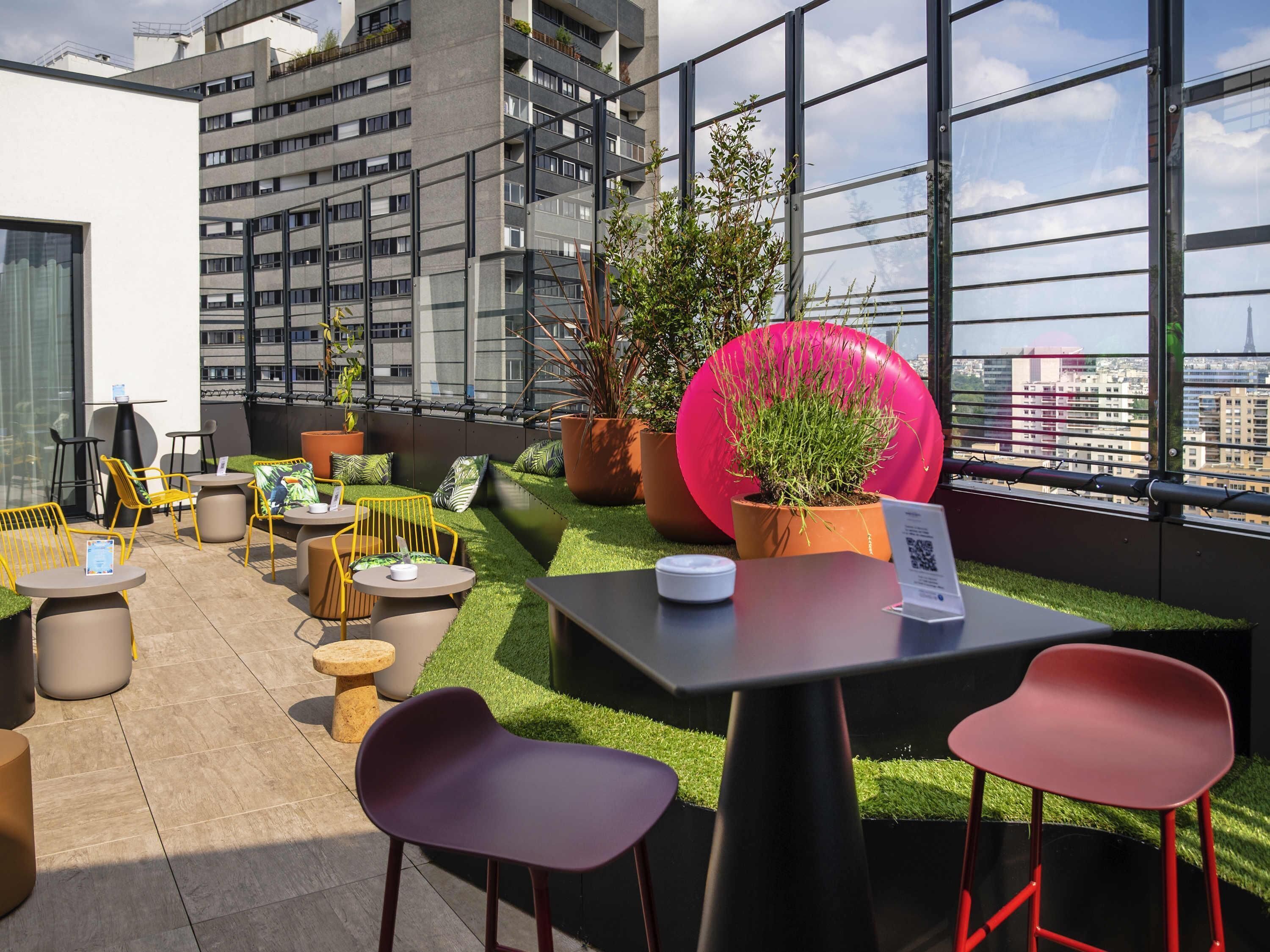 A rooftop terrace with outdoor seating, potted plants, and a view of the cityscape.