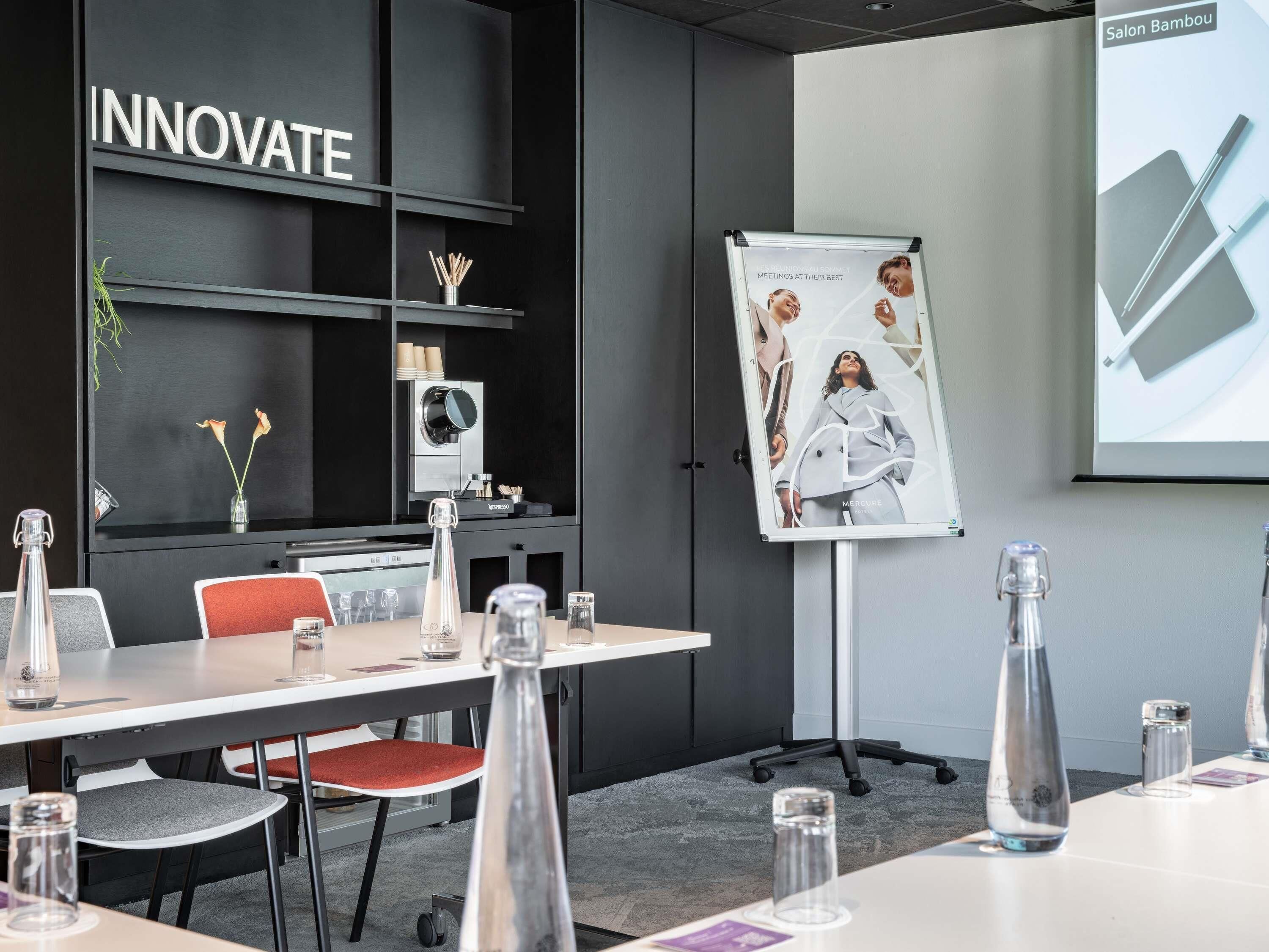 A modern meeting room with a whiteboard, a conference table, and a 'INNOVATE' sign on the wall.